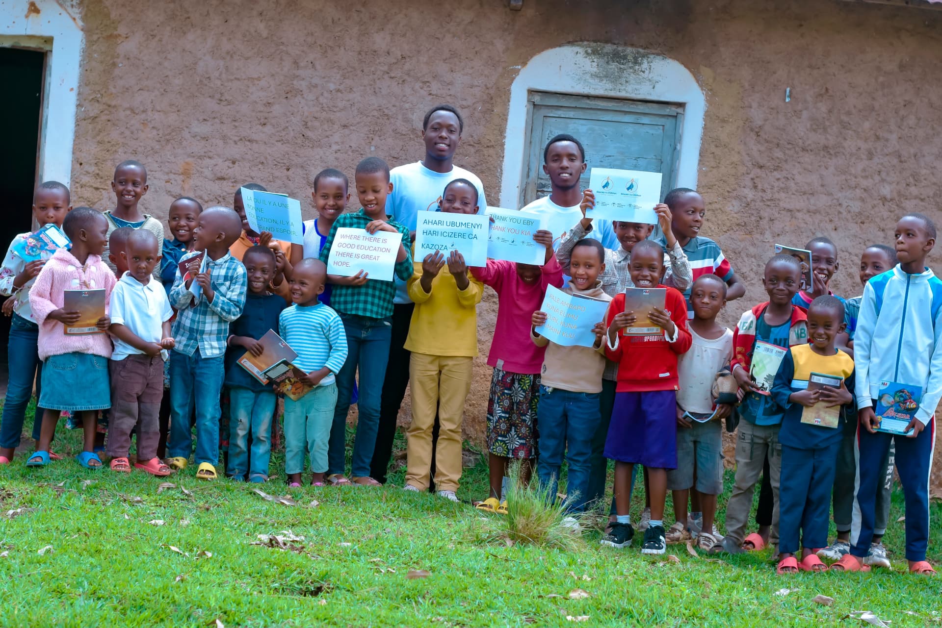 Children in Burundi holding new exercise books and handwritten messages about education and hope.