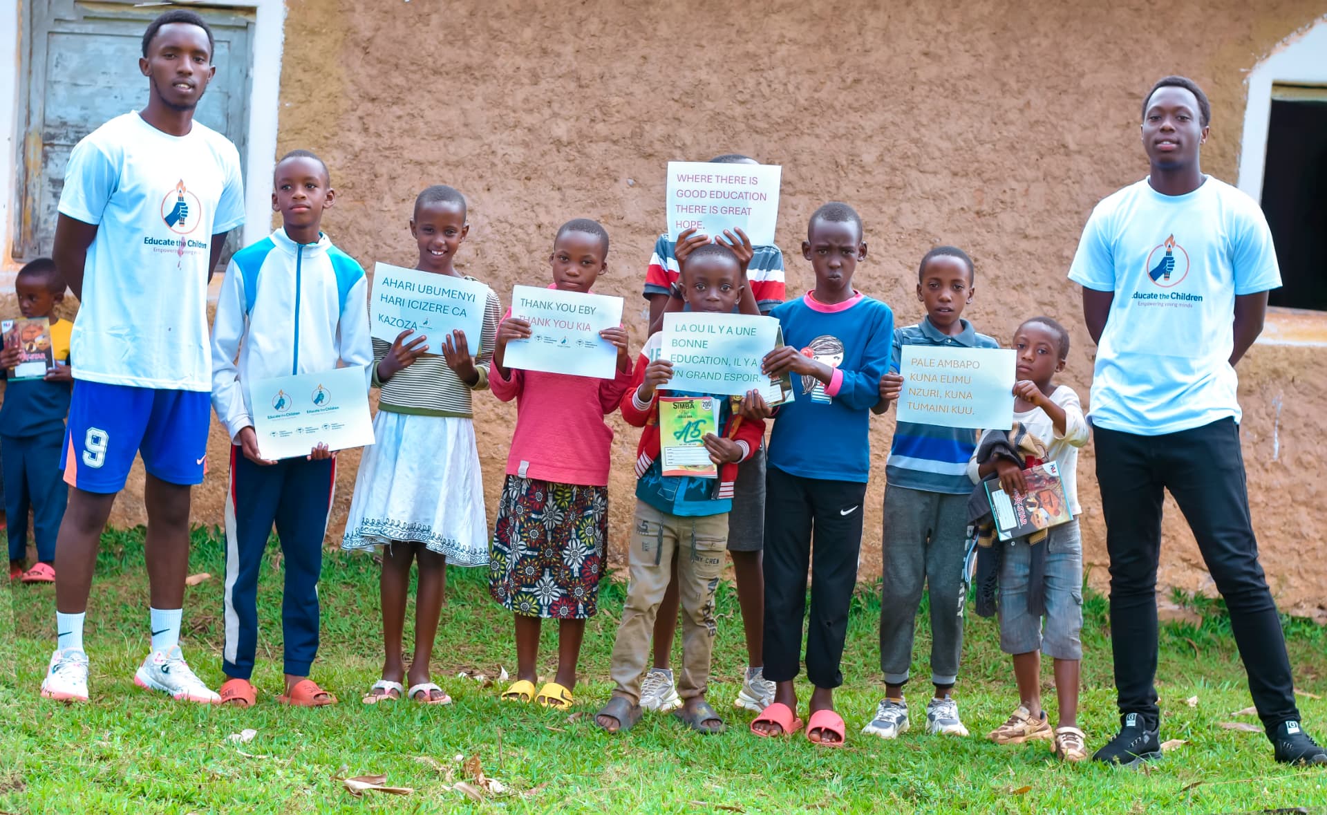 Children in Burundi holding handwritten signs in Kirundi, English, French and Kiswahili about education and hope.
